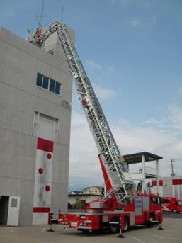 写真：建物にに梯子を掛けるはしご車の様子