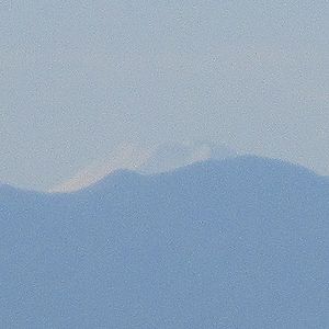 写真：秩父山脈からわずかに姿を見せる雪をかぶった富士山