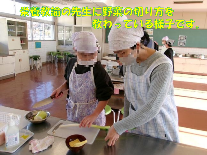 写真:栄養教諭の先生に野菜の切り方を教わっている様子です。