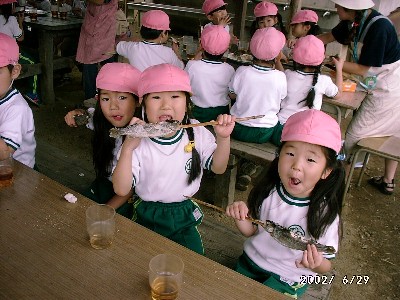 写真：串打ちしたマスの塩焼きをかぶりつく女の子たち