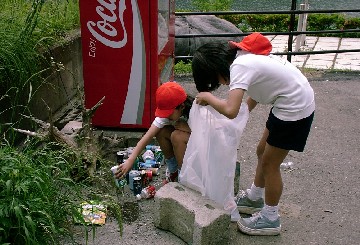写真：自販機の横で空き缶を拾う女の子たち