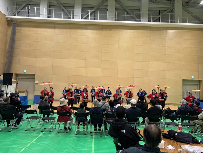 写真：第47回日立市産業祭　桐生八木節キャンペーンスタッフ室内ステージで、観客の前で唐傘を持って踊る様子