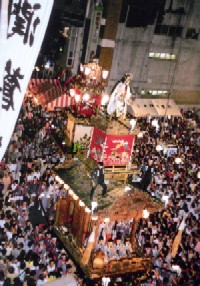 写真：祭りで鉾の周りを沢山の人が歩く様子