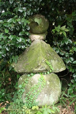 写真：草木の茂る中に立っている苔の生えた石造りの五輪塔