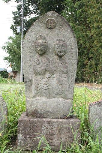 写真：四角い石の土台の上に男女のモチーフが半肉彫りされている
