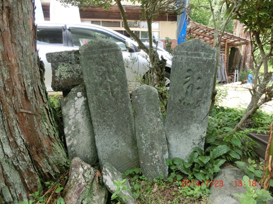 写真：木の根元に板碑が並べられている様子
