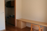 写真：一人用個室の白い壁と木製の机と椅子