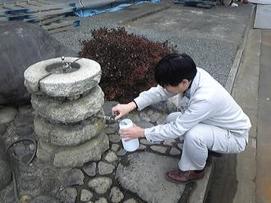 写真:給水栓水の水質検査のために給水栓の蛇口から水を汲んでいる様子