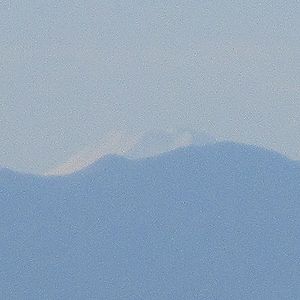 写真:秩父山脈からわずかに姿を見せる雪をかぶった富士山