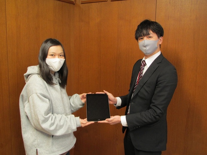 株式会社NTTドコモ様からタブレット端末を受け取る小島隊員の写真