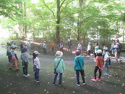 写真:木陰で輪になって今日の予定を聞く