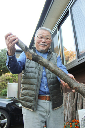 ヤマザクラの枝を手にお話する鈴木さんの写真