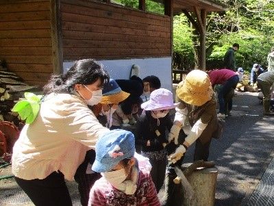 写真:家族で太をおさえる係、のごぎりを使う係と手分けして作業を進める様子