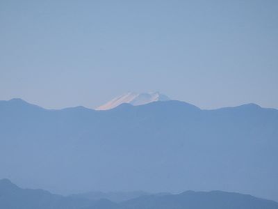 写真:水色の空、遠くに連なる青く見える秩父の稜線の上に白い富士山が見える