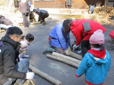写真:一人が木をしっかりと押さえ一人がドリルを使う