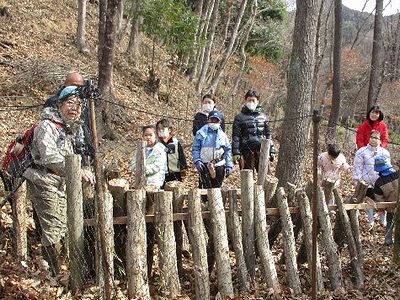 写真:一人が木をしっかりと押さえ一人がドリルを使う