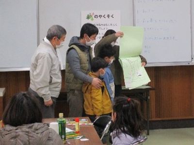 写真:大人が生きものマップを持ち子供が発表する様子