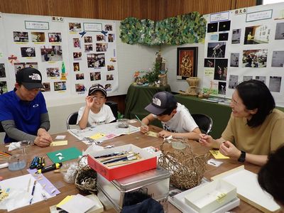 写真:家族でテーブルを囲み真剣にバッジを作る家族