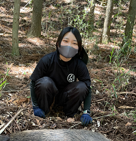 写真：捕獲したイノシシを前に微笑む細谷隊員