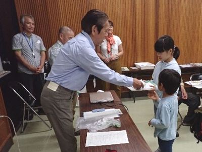 写真:所長から子どもたちへ賞状を渡す