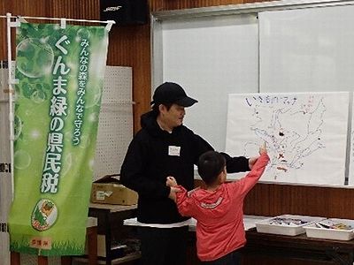 写真:生きものの絵を貼りつけた大きな地図の発表をする親子