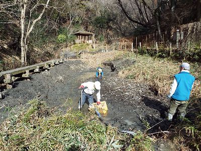 写真：長靴を履いてスコップを使って泥をかきだす職員たち