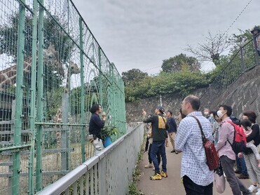 画像：過去のキーパーズトークの写真でキリン舎の前で来園者にキリンのお話をしている様子