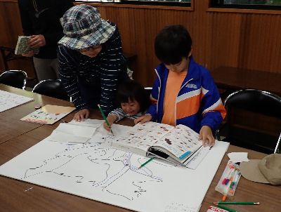 写真:マップと図鑑を広げて絵を描き込む親子