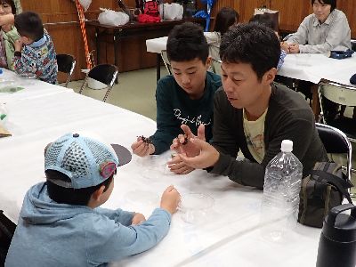 写真：カブトムシを手に持ち観察する親子