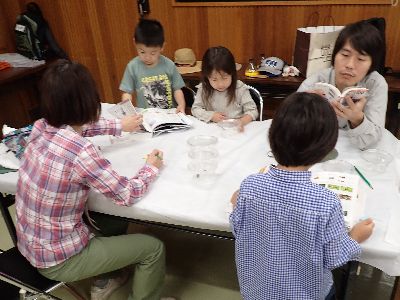 写真：虫の種名を図鑑で調べる親子
