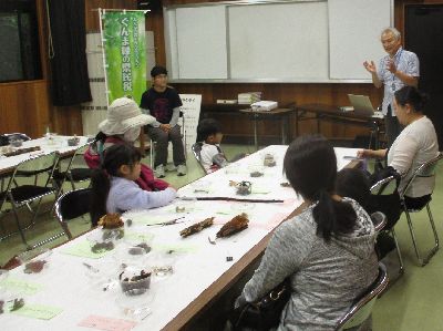 写真：キノコの並べられた机の周りに座る参加者